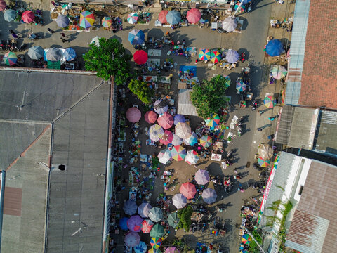 Aerial view of Pasar Pagi Pemalang featuring numerous colorful umbrellas covering market stalls with people walking through the busy aisles, Kecamatan Pemalang, Jawa Tengah, Indonesia.