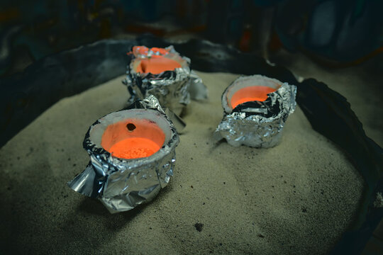 A Molten pot collection scorching molten hot lava refining furnace, precious metal smelting and industrial metallurgy. Precious metals being smelted and melted fashioned into artefacts.