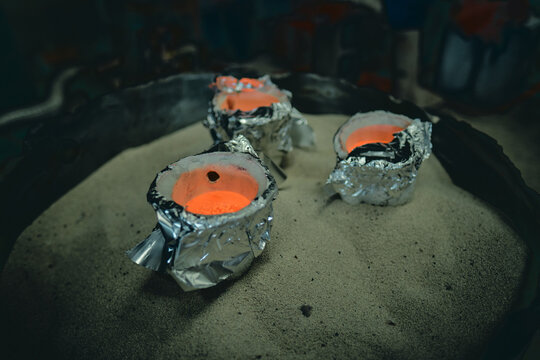 A Molten pot collection scorching molten hot lava refining furnace, precious metal smelting and industrial metallurgy. Precious metals being smelted and melted fashioned into artefacts.