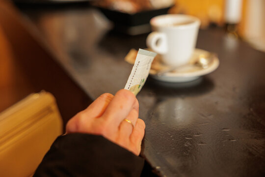 dettagli della mano di una donna adulta vestita in abiti invernali mentre si prepara per pagare con una banconota un caff&egrave; al bar