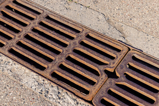 Brown metal storm drain grate on asphalt, construction site