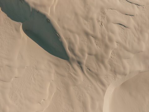Aerial view of the vast sand dunes at Birubi Point featuring intricate wind-swept patterns and soft shadows in Anna Bay, New South Wales, Australia.