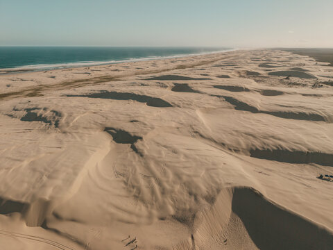 Aerial view of Birubi Point sand dunes stretching along the coastline with the ocean in the background in Anna Bay, New South Wales, Australia.