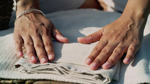 Reaching woman smoothing, folding napkin on blanket at park, preparing picnic, bangle