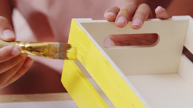 A large artist's brush stirs paints on a paint palette. Concept of DIY home decor, artistic hobby, art therapy, and domestic leisure.