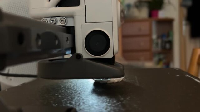 Close-up video of a mini 3D printer operating, printing at home