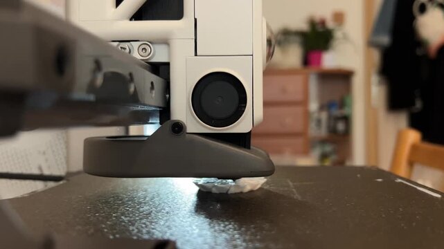 Close-up video of a mini 3D printer operating, printing at home