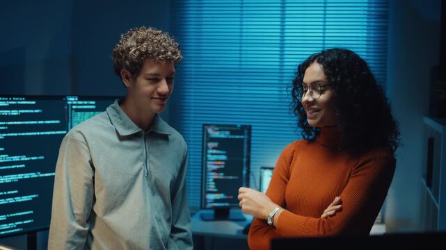 Diverse programmers give fist bump to celebrate success in dark office at night. Professional developer teamwork collaboration, Secure computer network system, Advanced cybersecurity AI data concept.