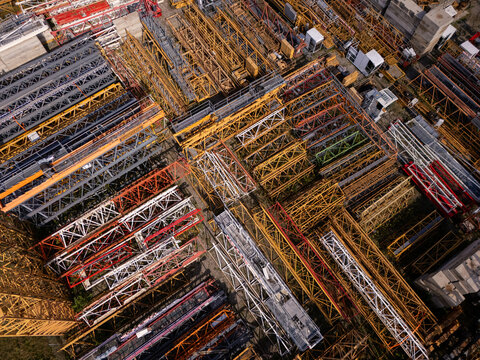 Aerial view of numerous yellow and red lattice crane sections stored in a construction yard in Gdansk, Poland.