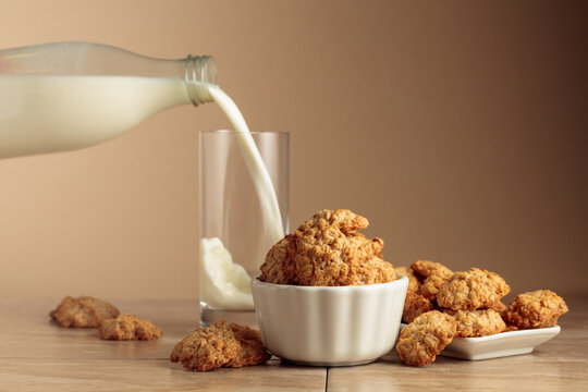 Oatmeal cookies and milk sit on a kitchen table.