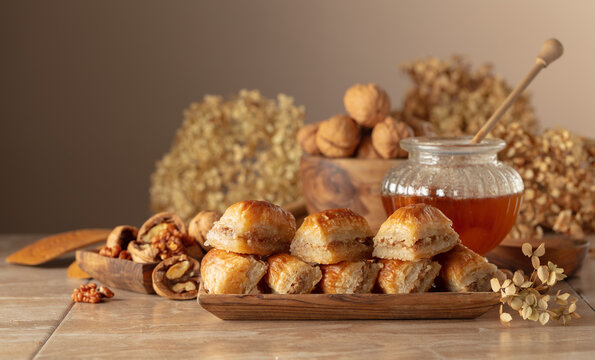 Baklava with walnuts and honey on a beige background.