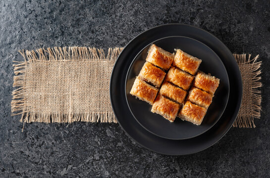 Baklava with walnuts on a blackstone table.