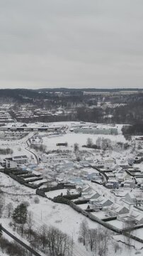 Aerial drone view showing snow covered homes roads commercial buildings and wooded hills across Storas during winter in Angered Gothenburg Sweden