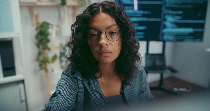 Young black female developer wear glasses writes complex software code at desk in office. Artificial intelligence machine learning, Secure computer network, Advanced cloud data analysis trend concept.