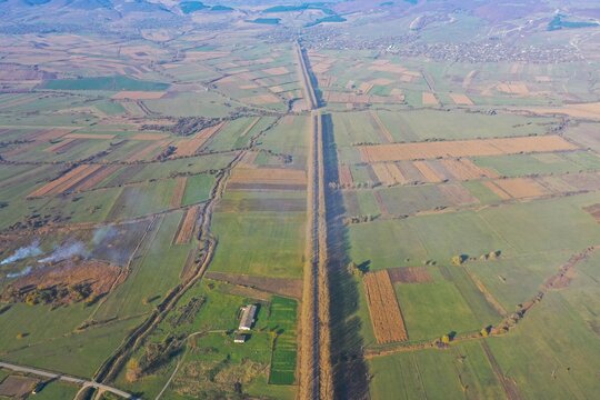 Aerial view of agricultural fields and a long tree-lined road in the rural landscape of Tbilisi, Mtskheta-Mtianeti, Georgia.