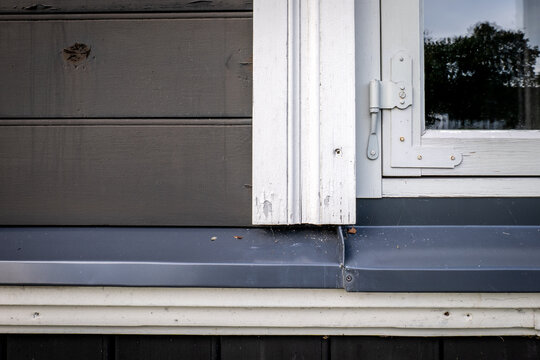 Weathered Window Joinery Detail with White Hinge and Gray Metal Sill