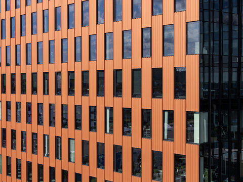 Aerial view of modern office building facade with vertical orange panels and reflective glass windows in Gdansk, Poland.