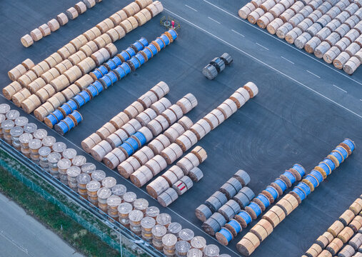 Aerial view of large wooden industrial reels arranged in organized rows at an outdoor storage yard, representing industrial supply chain infrastructure in Livorno, Tuscany, Italy.