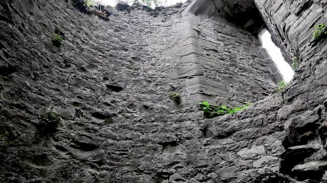 Upward view of historic arrow slits and windows within the formidable stone walls of an old castle in the UK.
