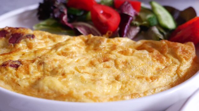 Close up dynamic motion of fluffy omelette served with fresh salad and tea