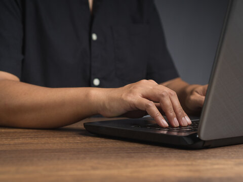 Person typing on laptop at wooden desk