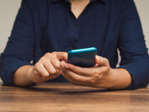 Person using smartphone at wooden table