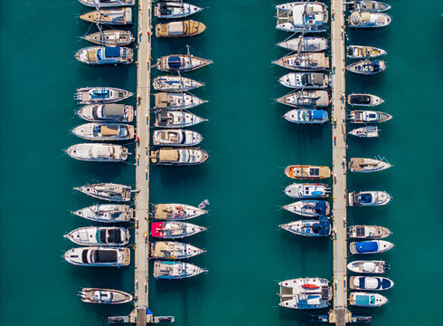 Aerial view of Limassol Marina featuring rows of yachts and sailboats moored at concrete piers in the turquoise waters of the Mediterranean Sea in Lemesos, Lemesos, Cyprus.