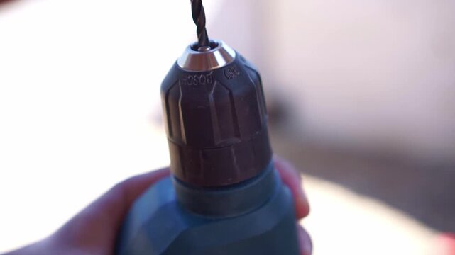 Close up of hand installing drill bit into power drill chuck, DIY hardware tool setup, workshop equipment footage scene.