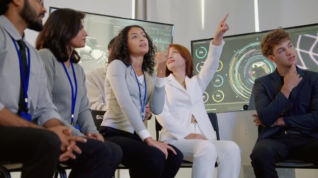 Diverse technology professionals collaborating during a team discussion while reviewing digital data, analytics dashboards, and technology projects in a modern office.
