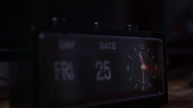 finger pressing button on analog alarm clock, dark room setting, morning wake up and time management concept.