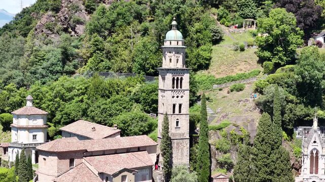 Scenic view of Santa Maria del Sasso church in Morcote, Ticino, Switzerland, with its historic bell tower rising among lush hillside gardens near beautiful Lake Lugano.