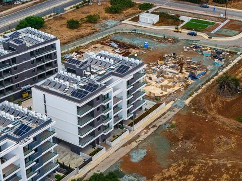 Aerial view of modern residential apartment buildings with solar panels on the rooftops, situated in a developing urban area in Lemesos, Lemesos, Cyprus.