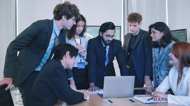 Diverse professionals collaborating around a laptop and documents during a business meeting, representing teamwork, project planning, technology, innovation, and professional collaboration.
