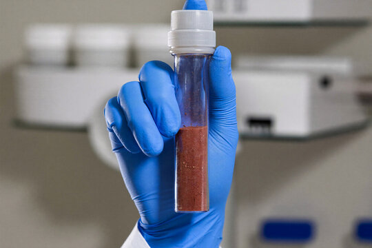 Scientist holding test tube with red Martian soil sample