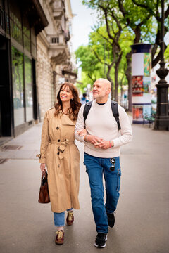 Smiling brunette haired woman and a handsome mature man walking together on a street in Budapest