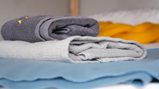 Neatly folded towels stacked on shelf with blurred background of braided material