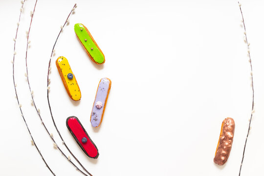 Colorful gourmet eclairs with glazed topping - modern pastry flat lay in soft natural light, top view dessert concept