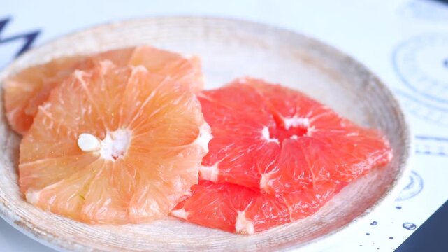 Close up of fork piercing juicy pink grapefruit slices on a plate ready for eating