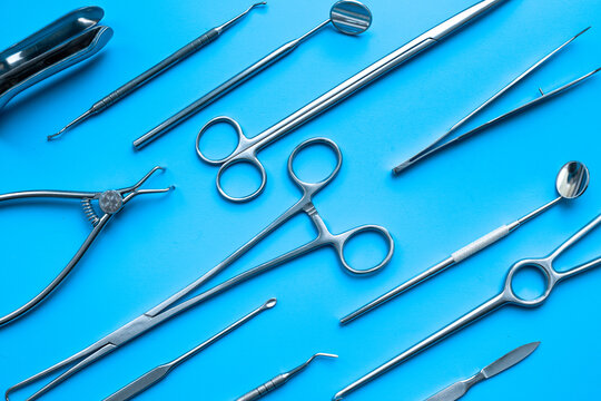 A lot of stainless surgical instruments and tools on blue table, top view. Medical background