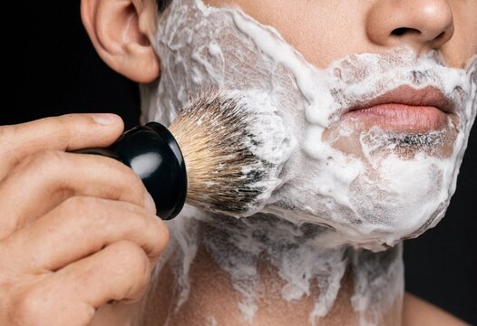 Close-up of a man applying thick white shaving foam on his face with a professional shaving brush for a clean shave