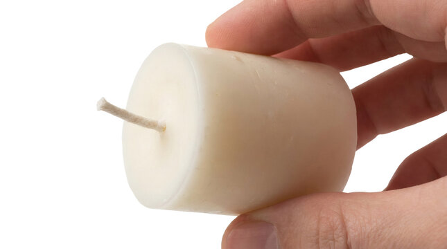 Human hand holding a small white paraffin wax pillar candle with a wick mockup isolated on transparent background.