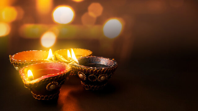 Decorated clay diya lamps lit during the Diwali festival of lights against a glowing golden bokeh background. Diwali festival celebration