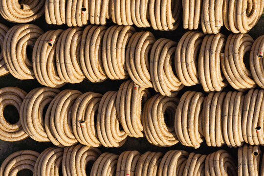 Aerial view of rows of coiled corrugated drainage pipes stacked in a storage yard in Enschede, Overijssel, Netherlands.
