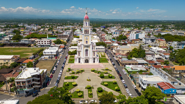 Aerial view of the Church of the Sacred Heart of Jesus featuring its prominent central tower and surrounding plaza in the urban landscape of Moca, Espaillat Province, Dominican Republic.