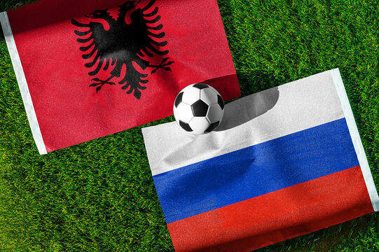 Albania vs. Russia football match. National flags on green grass with soccer ball in the middle. Football background for international match.
