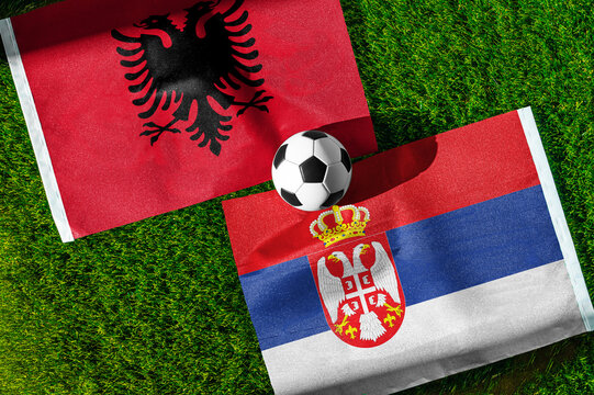 Albania vs. Serbia football match. National flags on green grass with soccer ball in the middle. Football background for international match.