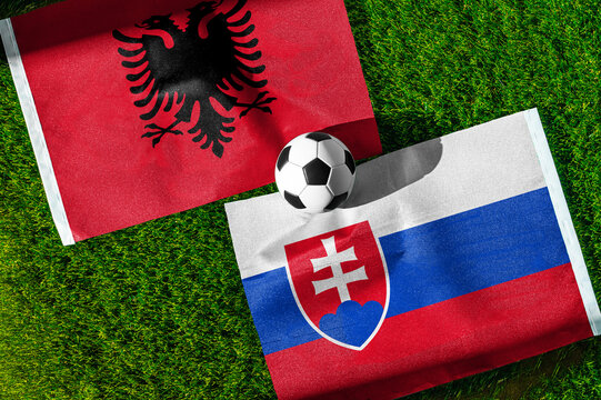 Albania vs. Slovakia football match. National flags on green grass with soccer ball in the middle. Football background for international match.