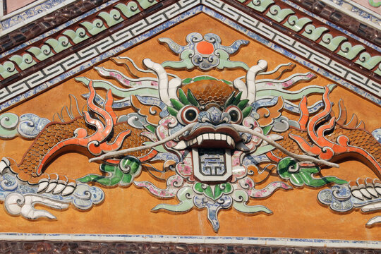 Traditional imperial dragon relief sculpture on triangular pediment, symmetrical temple tympanum ceramic mosaic design with ochre stucco background