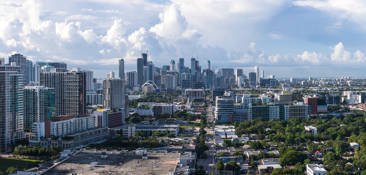 Aerial view of Midtown Miami skyline featuring modern high-rise buildings, urban density, and lush greenery under a bright blue sky in Miami, Florida, United States.