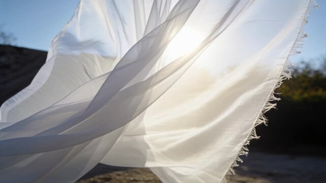 Billowing white frayed cloth opening and twisting across open land from light breeze, sun glowing